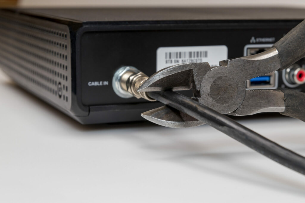 Image shows wire cutter cutting the cord from a cable box
